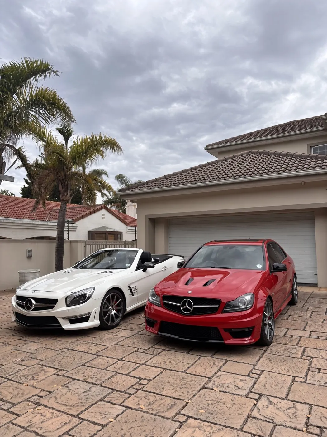 White Mercedes-AMG SL 65 and red C63 AMG Edition 507 parked on the driveway